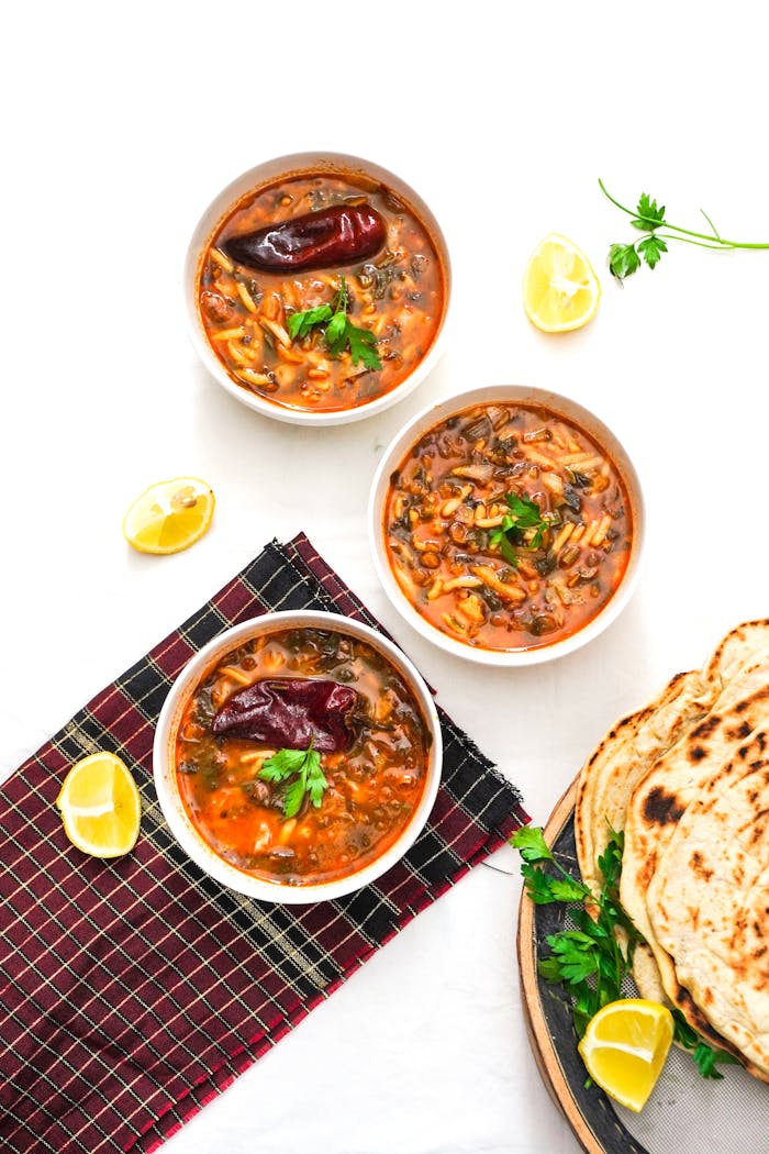 services-03 Tasty Moroccan Harira soup bowls with herbs, lemon slices, and fresh flatbread for a flavorful meal.