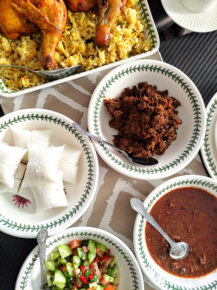 about-us Top view of a vibrant African meal featuring chicken, rice, salad, and sauces in ceramic bowls.